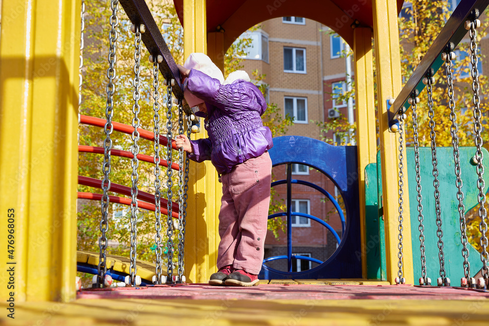 child walks on a playground on an autumn sunny day.