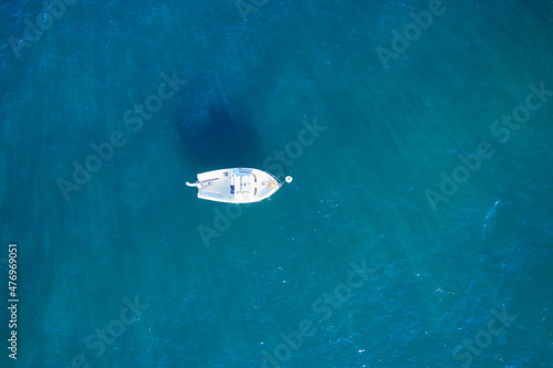 Empty fishing boat from high above in atlantic. Aerial view of small white ship on blue sea water. Isolated object.