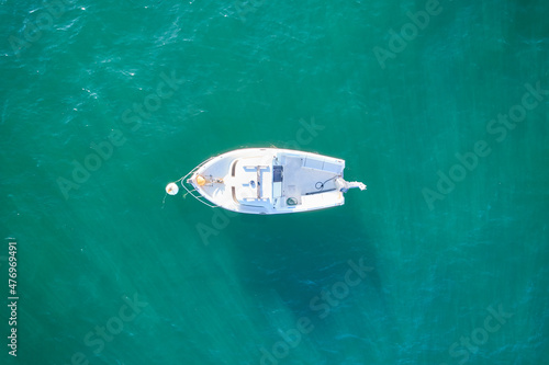 Empty fishing boat from high in atlantic. Aerial view of small white ship on green sea water. Isolated object. France.