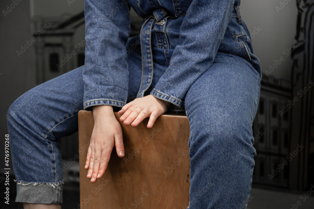 Close-up, a woman in a denim suit plays the cajon.
