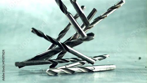 Drill bits fall on the table. On a gray background. Filmed is slow motion 1000 frames per second. High quality FullHD footage photo