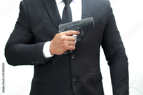 A man in a black bodyguard suit is holding a pistol at chest level ready to keep the VIPs safe. White background isolate.