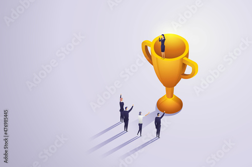 Winning team has businesswoman standing on trophy.