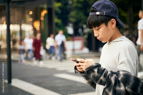 teenage asian boy using mobile phone outdoors