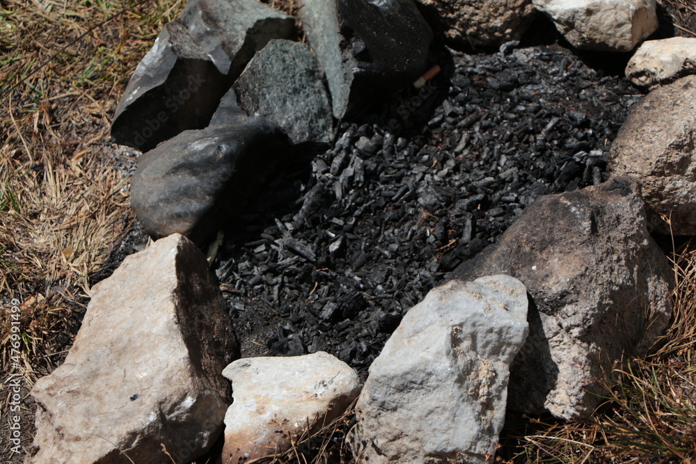 Extinguished charcoal among the stones after a picnic or camp.
