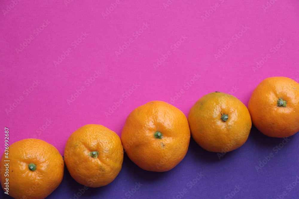 Mandarins. Tangerine. Purple and pink background. Copy space. Tangerines lined up on a pink and purple background Mandarins. Tangerine. Purple and pink background. Copy space. Tangerines lined up on a pink and purple background