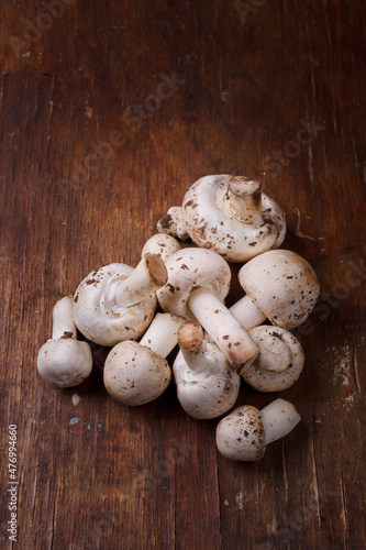 Fresh champignons on wooden table. Seasonal ogranic healthy food, ketogenic diet. Mushrooms on rustic background. Close up vertical shot, close up.