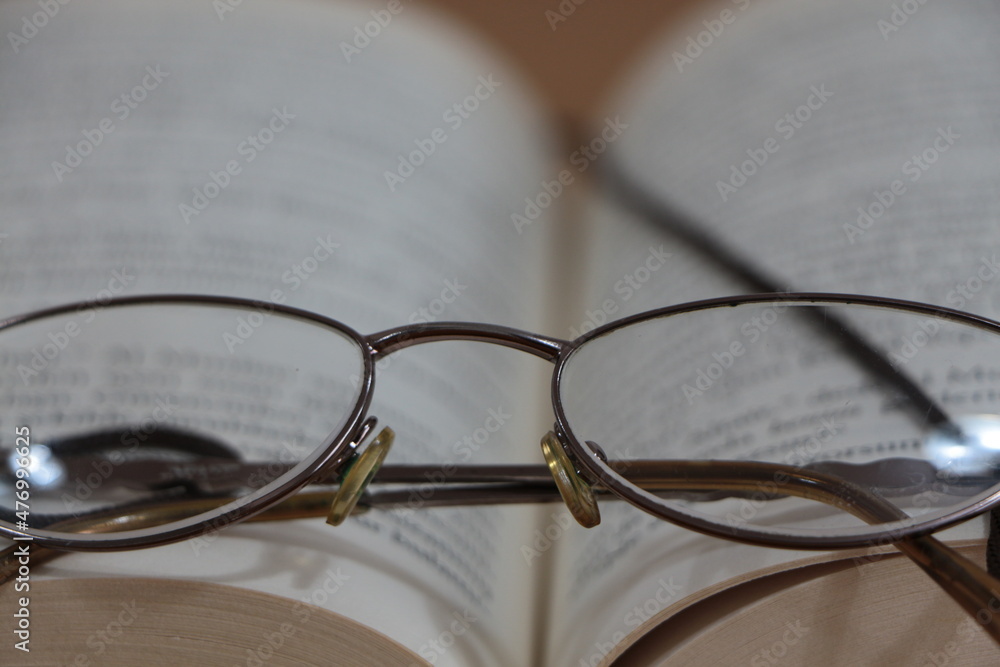 Close up the reading glasses on the open book. Close up the reading glasses on the open book.
