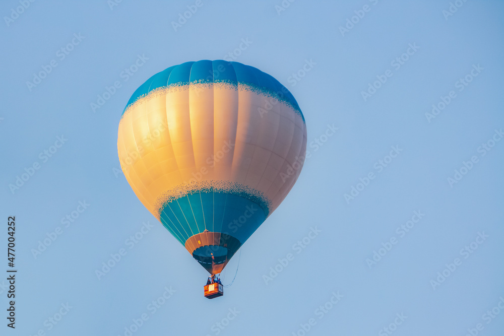 Fototapeta premium a blue balloon at dawn in the blue sky. the sun's rays are reflected