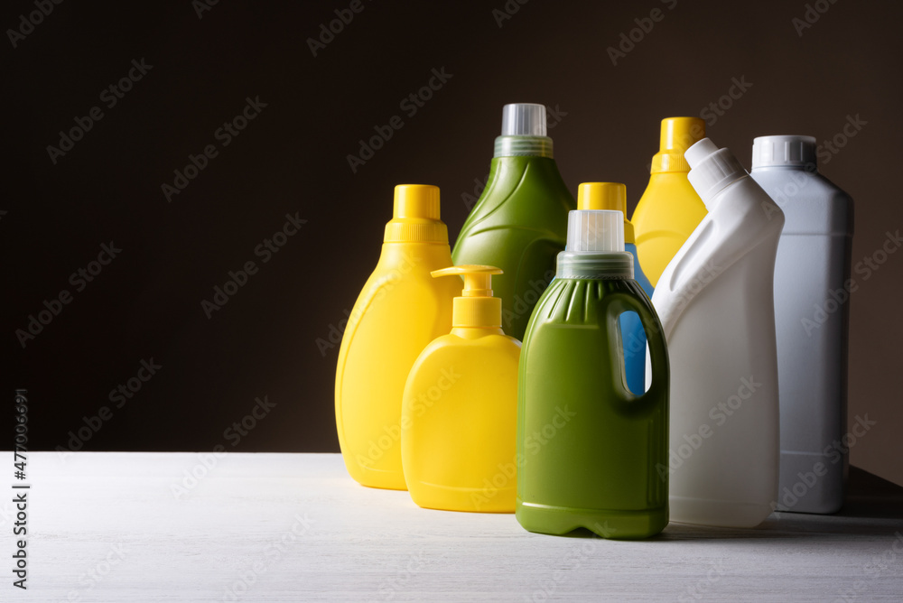Colorful plastic detergent bottles on the table on the dark background. Colorful plastic detergent bottles on the table on the dark background.