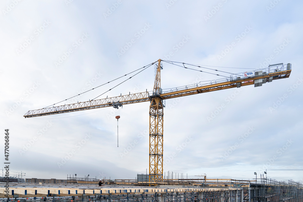 Construction site with tower crane for lifting building materials and the sun in a blue sky