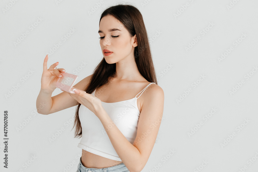 Portrait of pretty girl opening new contouring palette with bronzer, highlighter and a blush, over white color background. Receiving gifts concept Portrait of pretty girl opening new contouring palette with bronzer, highlighter and a blush, over white color background. Receiving gifts concept