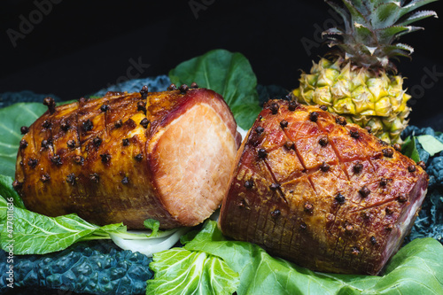 фотографія Cooked gammon joint with whole pineapple against a black background