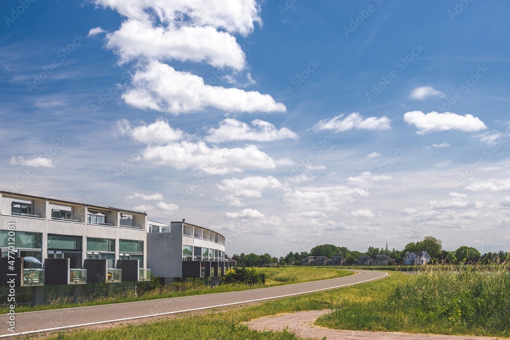 Sunny summer day at Netherlands suburb. Modern architecture residential houses and green nature across the road.