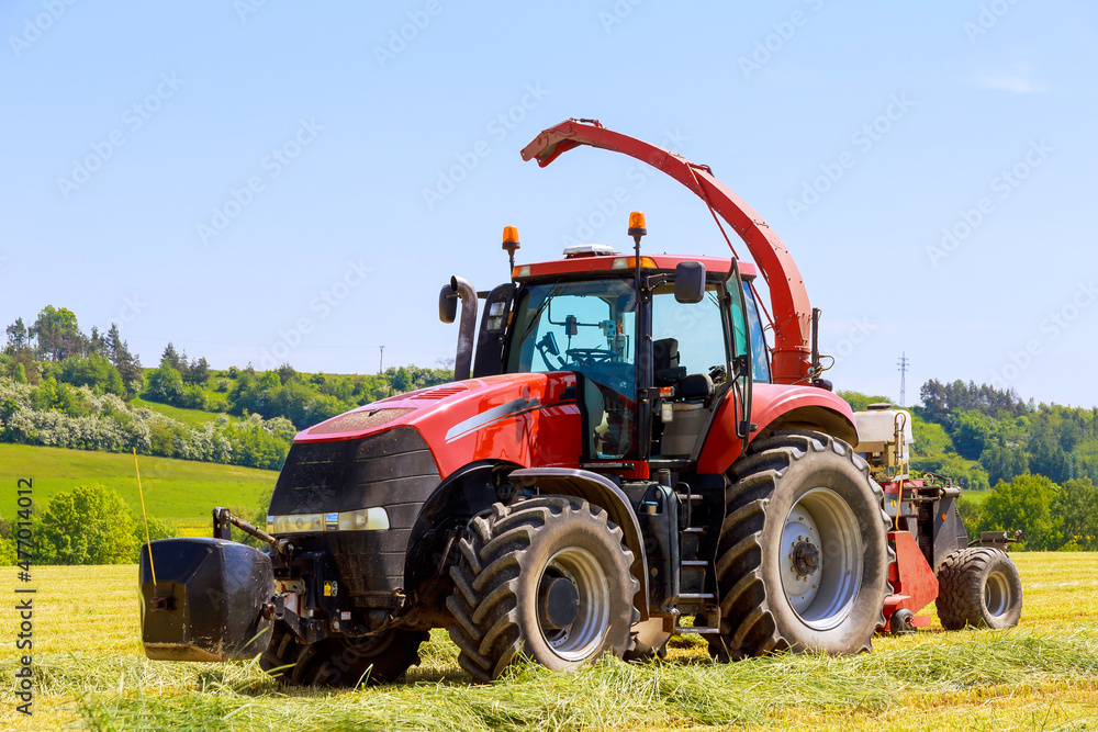 Red tractor in the field, agricultural machinery harvesting. Feed for cows for the winter. Red tractor in the field, agricultural machinery harvesting. Feed for cows for the winter.