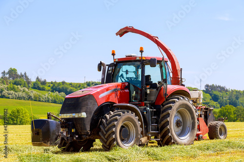 Red tractor in the field  agricultural machinery harvesting. Feed for cows for the winter.