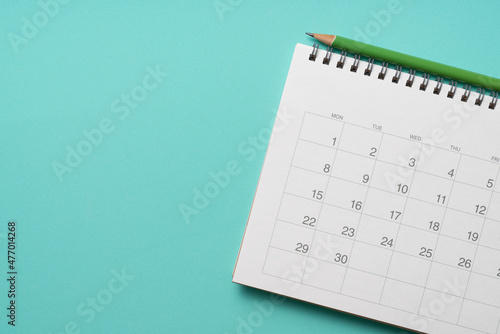 close up of calendar and pencil on the green table background, planning for business meeting or travel planning concept
