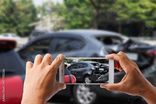 Close-up hand holding smartphone and take photo of car accident for insurance.