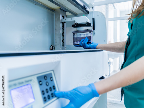 Laboratory assistant works with automatic multi slides stainer at the modern laboratory.