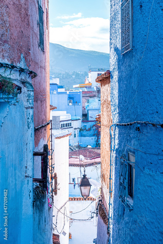 Traditional antique lamp on the corner of a old blue colored residential building of Chefchaouen with mountain in the distant © Aerial Film Studio