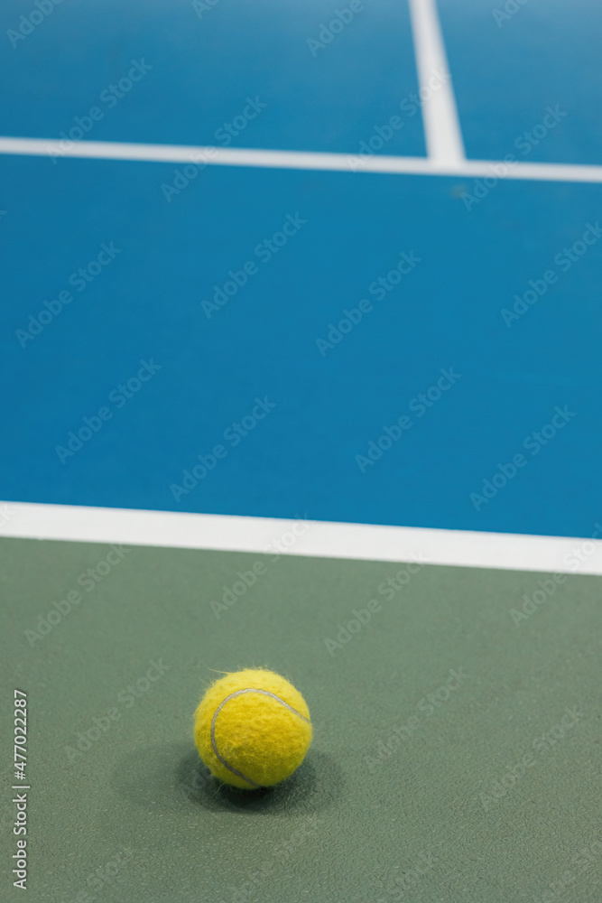Yellow tennis ball on the blue and green hard court