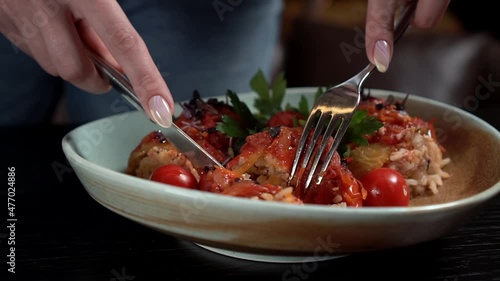 Restaurant customer trying dish with fork and knife. Close-up woman hands.