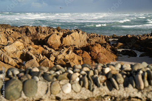 Coast in France. Brown rocks in front of water with waves against blue sky. Famous surf spot in the La Torche in the Brittany near Plomeur. photo