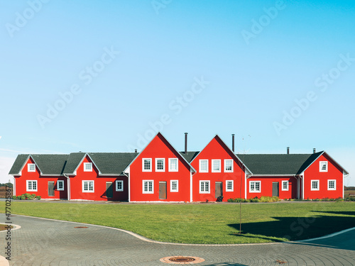 red Scandinavian houses, white edging, summer, blue sky, cobblestone road,