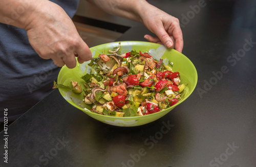 Close up view of woman stirring vegetarian salad in salad bowl. 