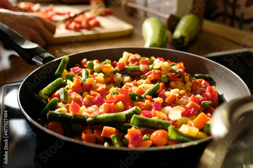 Valokuva Frying-pan with fresh vegetables chopped for stew on electric stove by kitchen t