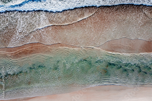 Aerial of aqua Atlantic ocean and white sea foam rolling in over a Florida beach.