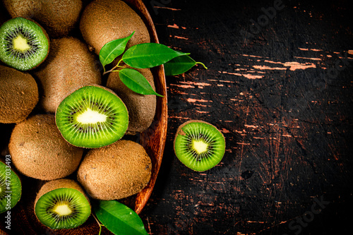 Fotografie, Obraz Fresh kiwi with leaves on a wooden plate