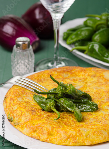 Table with a plate containing a Spanish omelette and green peppers from Padron.