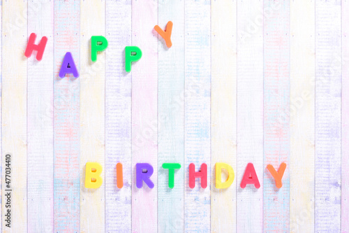 Photograph of some magnet letters with the English text of Happy Birthday on a colored cardboard background.The photograph is taken in horizontal format and from an overhead point of view. photo