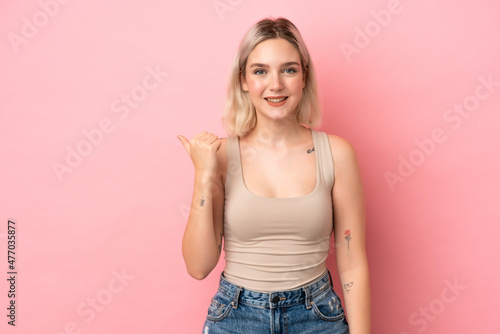 Young caucasian woman isolated on pink background pointing to the side to present a product