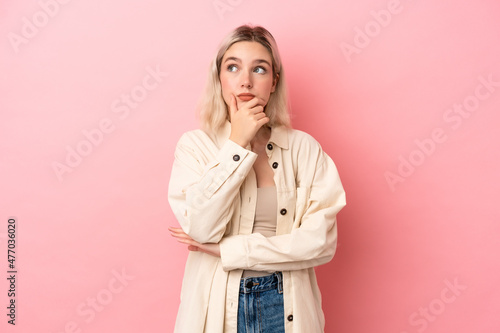 Young caucasian woman isolated on pink background having doubts and with confuse face expression