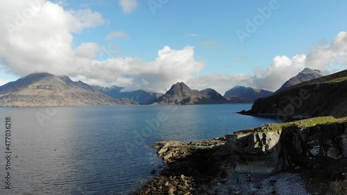 Rare aerial footage capturing a cinematic shot of the Cullin Mountain range in full from the south of The Isle of Skye on a small headland town called Elgol near the Scottish Highlands. photo