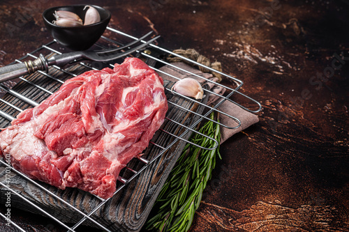 Ready for cooking on grill Boneless lamb meat, raw neck meat with herbs. Dark background. Top view. Copy space