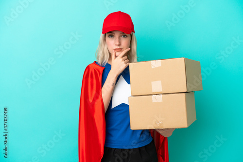 Super Hero caucasian delivery woman isolated on blue background thinking