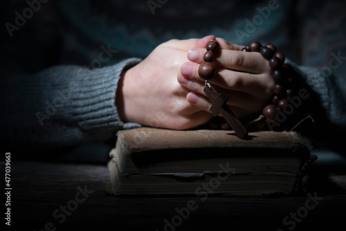 Portrait of young beautiful girl praying to God with rosary. Horizontal image.
