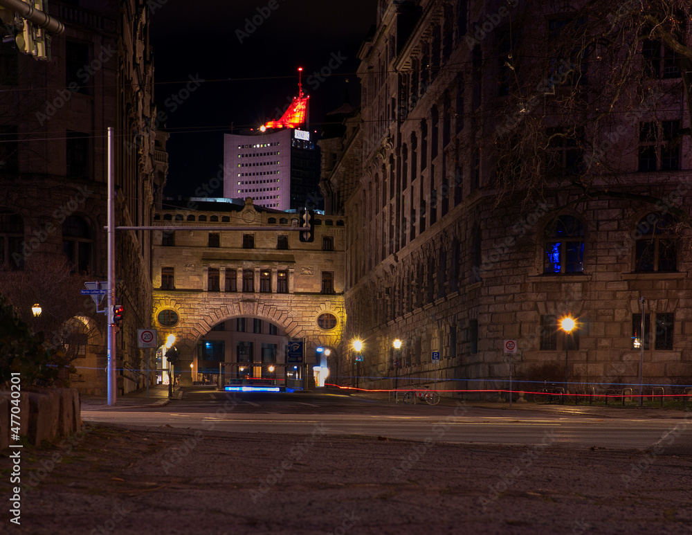 Fototapeta premium Historischer Beamten-Übergang am Neuen Rathaus Leipzig bei Nacht, beleuchtete Architektur mit City-Hochhaus im Hintergrund, Leipzig, Sachsen, Deutschland