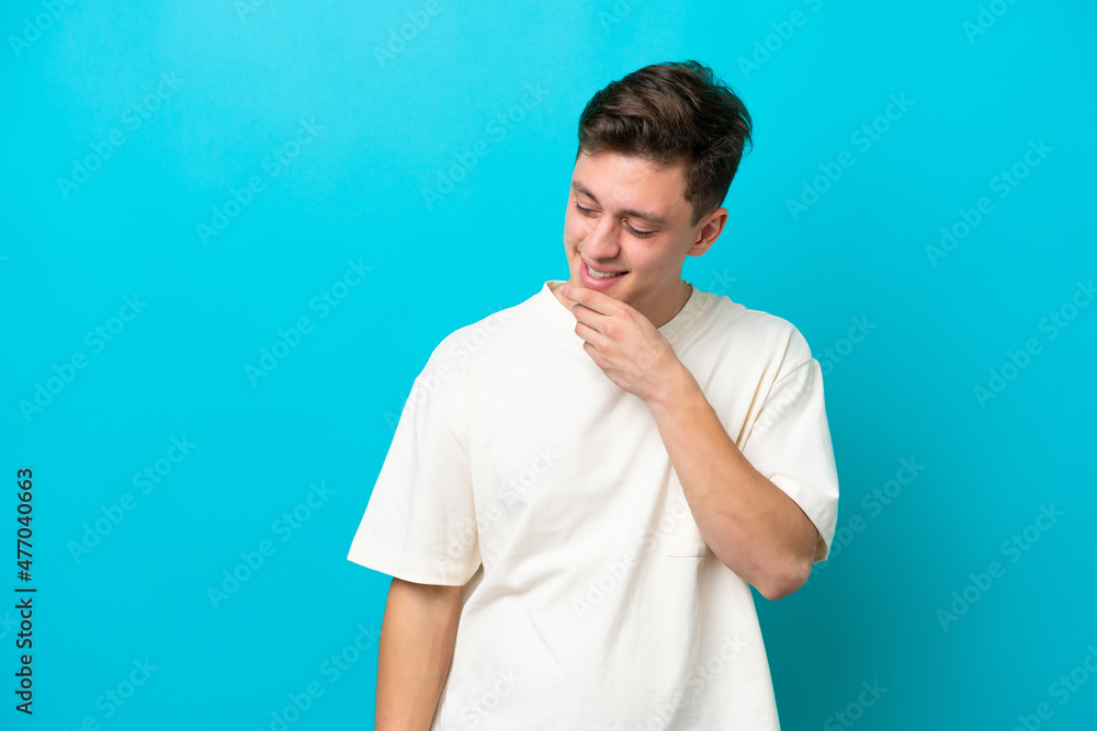 Young handsome Brazilian man isolated on blue background looking to the side and smiling Young handsome Brazilian man isolated on blue background looking to the side and smiling