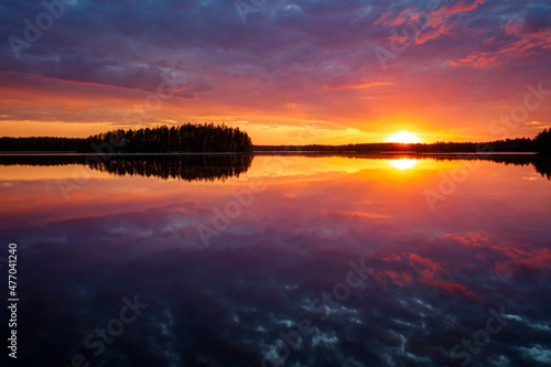 Scenic and beautiful sunset and colorful, dramatic cloudy sky and their reflections on a calm lake in Finland at summer.
