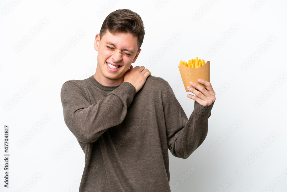 Young Brazilian man holding fried chips isolated on white background suffering from pain in shoulder for having made an effort Young Brazilian man holding fried chips isolated on white background suffering from pain in shoulder for having made an effort
