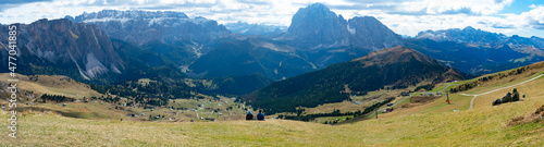 Couple sitting overlooking Dolomites in European Alps. Gardena Pass, Italy