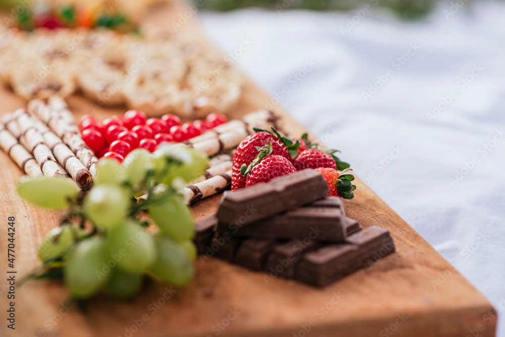 Fototapeta Tabla de madera con distintas frutas golosinas y panes con fondos fuera de foco