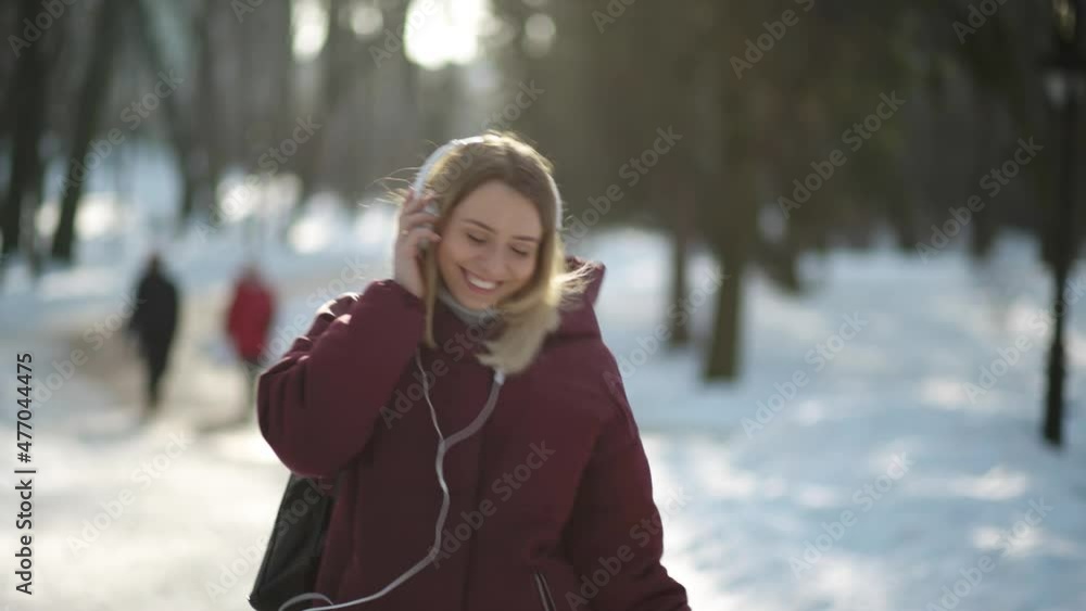 Slow motion of happy young woman in headphones dancing outdoors in the city park having fun alone. Joyful attractive blonde carefree woman listening to music with smartphone Slow motion of happy young woman in headphones dancing outdoors in the city park having fun alone. Joyful attractive blonde carefree woman listening to music with smartphone