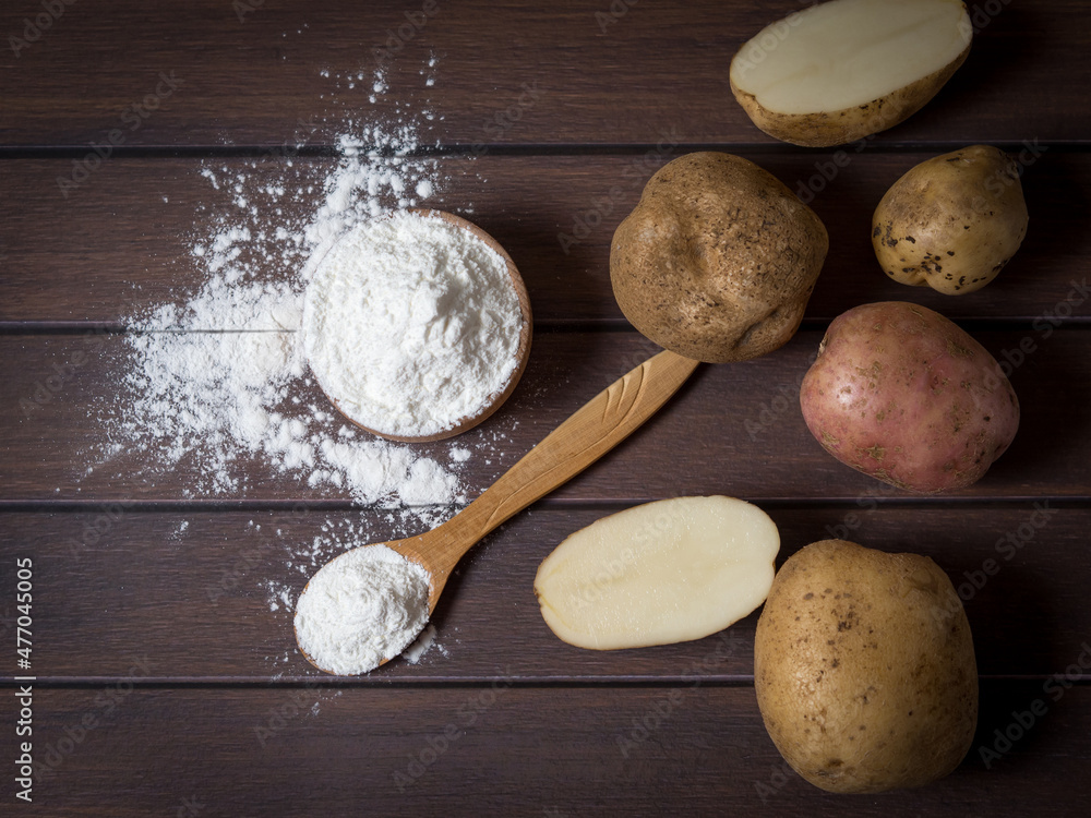 Potato starch with potatoes on a dark wooden background. Potato starch with potatoes on a dark wooden background.