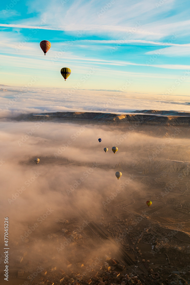 Hot air balloons flying over spectacular Cappadocia. Beautiful view of hot air balloons floating in sunrise blue sky over the mountain landscape of fairy chimneys Hot air balloons flying over spectacular Cappadocia. Beautiful view of hot air balloons floating in sunrise blue sky over the mountain landscape of fairy chimneys