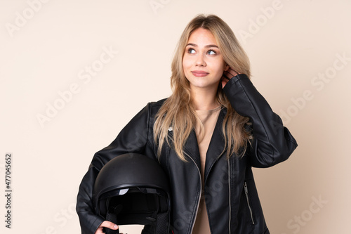 Russian girl with a motorcycle helmet isolated on beige background thinking an idea